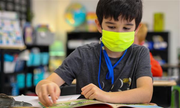 student smiles at camera while working at desk